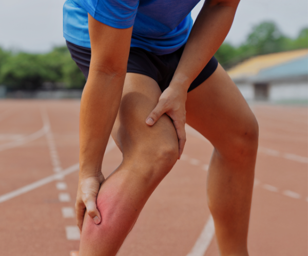 Runner holding sore calf muscle with visible swelling and pain